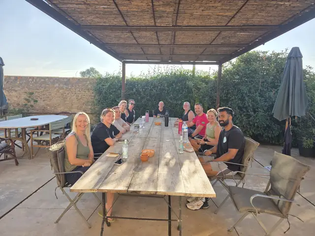 A Let Luce retreat group sitting together at a long wooden table under a pergola, smiling at the camera.