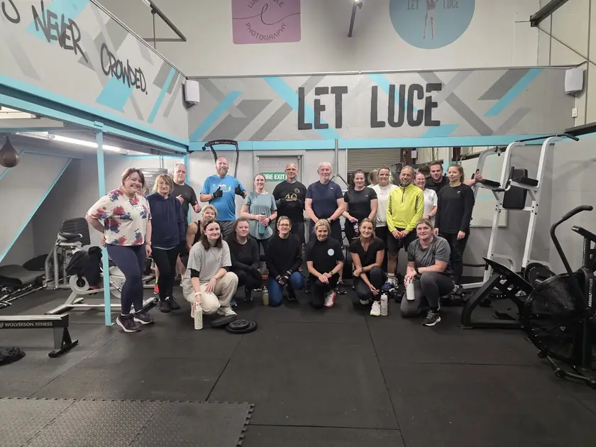 Lucy's crew gathered in the bright blue and grey gym, with LET LUCE painted across the wall.