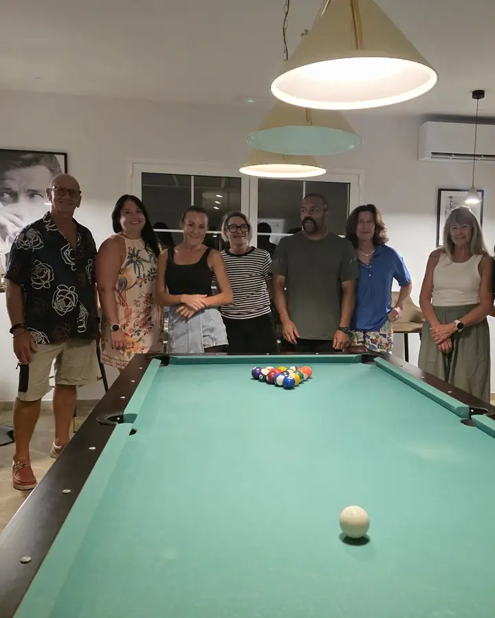 Guests standing round a pool table in the villa games room.