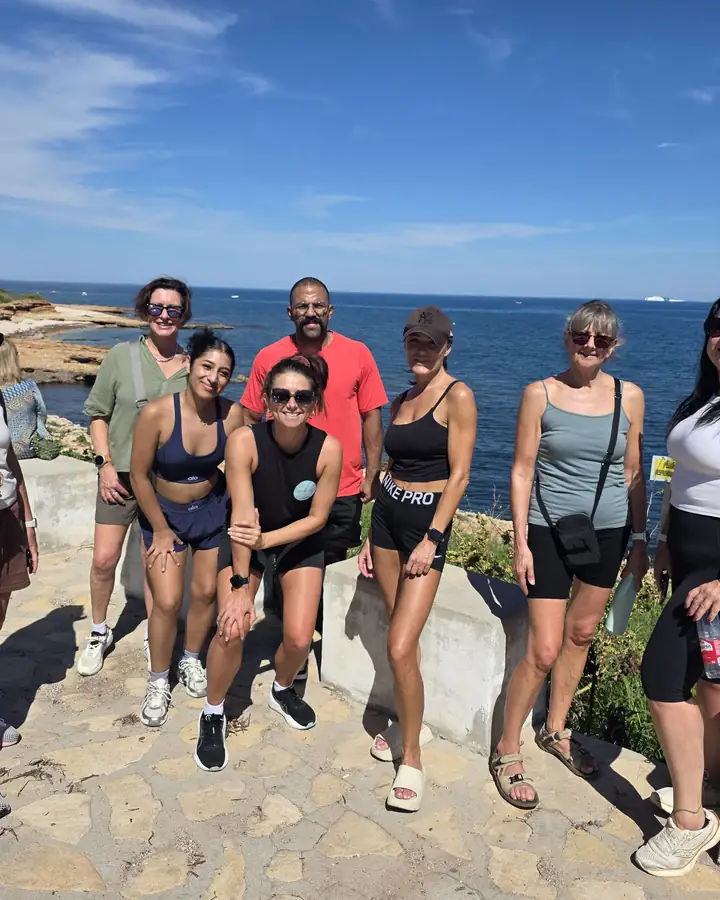 Retreat guests smiling together on the coast path with the sea behind.